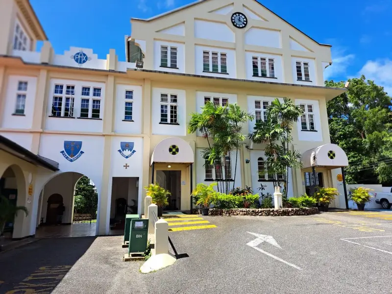 The imposing facade of Saint Benedict's Monastery, bathed in sunlight, features a clock tower and arched entrances.