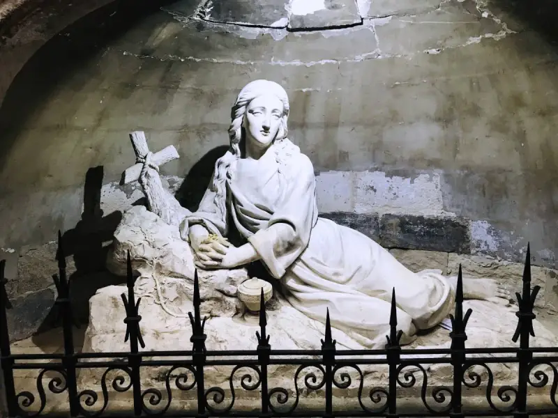 Sculpture of Mary Magdalene in repose, near a cross, possibly at her burial site.