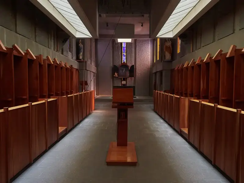 Rows of wooden stalls line the interior of a Carthusian monastery, leading towards an altar.