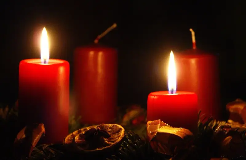 Two red candles glow, marking the 2nd advent. A festive wreath with dried orange slices and pine needles surrounds them.